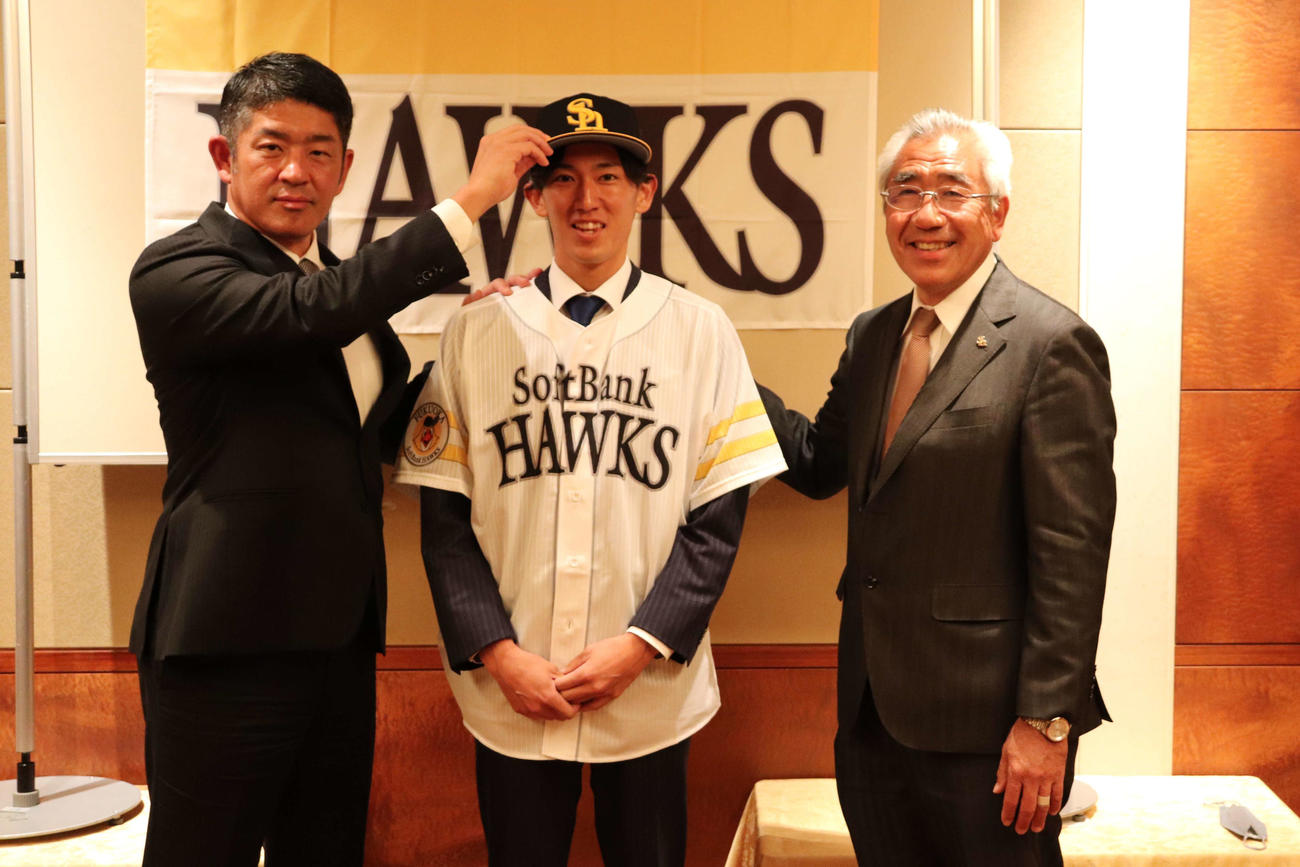 （写真左から）福山アマスカウトチーフに帽子をかぶせてもらい、照れくさそうに笑顔を見せる大津。右は宮田アマスカウト（撮影・保坂淑子）