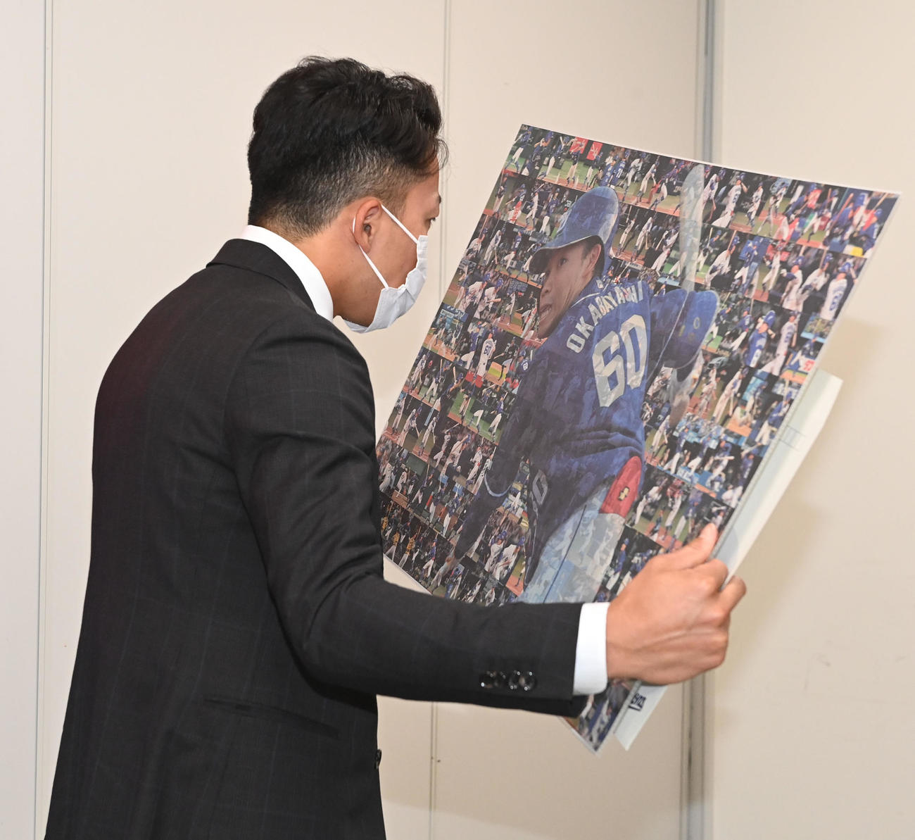 大幅アップで契約更改の岡林は今シーズンの全安打の写真をじっくりと見る（撮影・前岡正明）