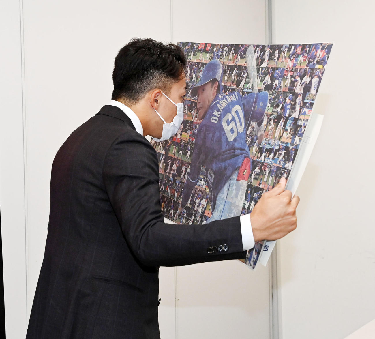 大幅アップで契約更改の岡林は今シーズンの全安打の写真をじっくりと見る（撮影・前岡正明）