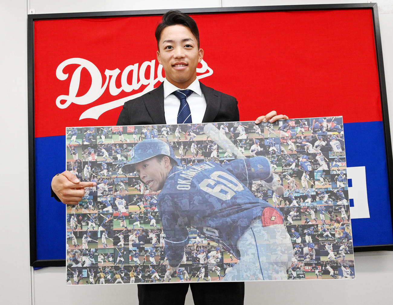大幅アップで契約更改の岡林は今シーズンの全安打の写真を手に笑顔を見せる（撮影・前岡正明）