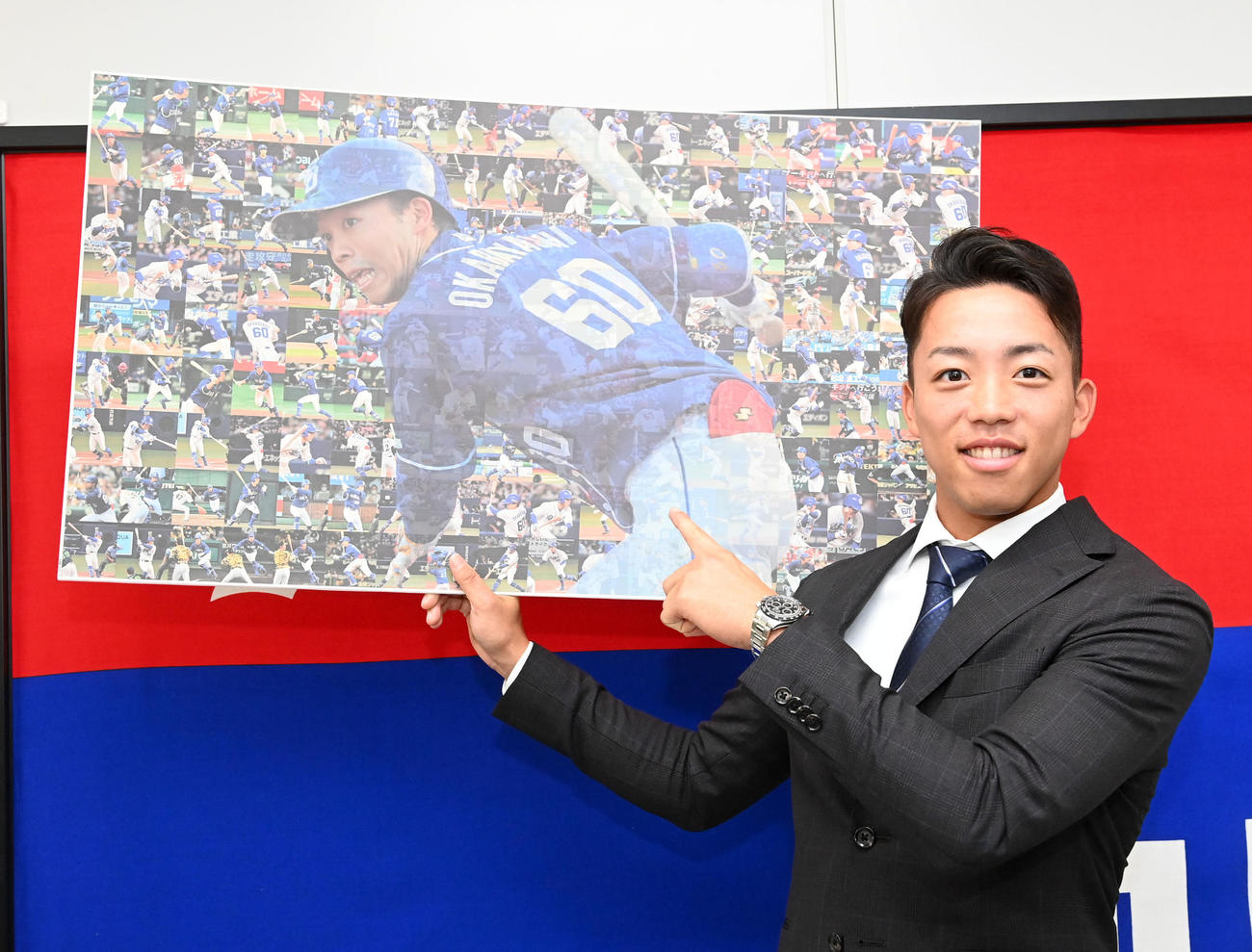 大幅アップで契約更改の岡林は今シーズンの全安打の写真を手に笑顔を見せる（撮影・前岡正明）