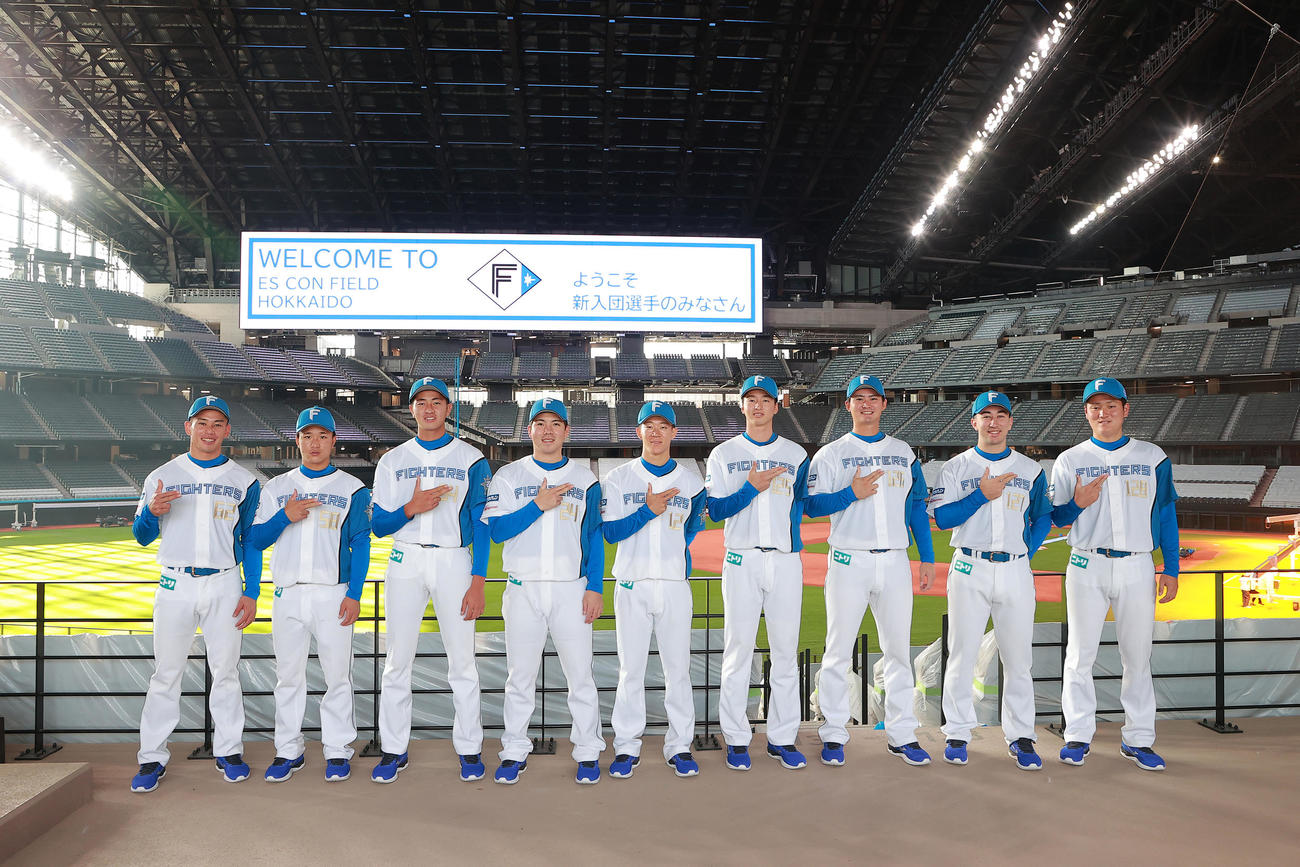 新球場のグラウンドをバックにガッツポーズする新入団選手たち（球団提供）