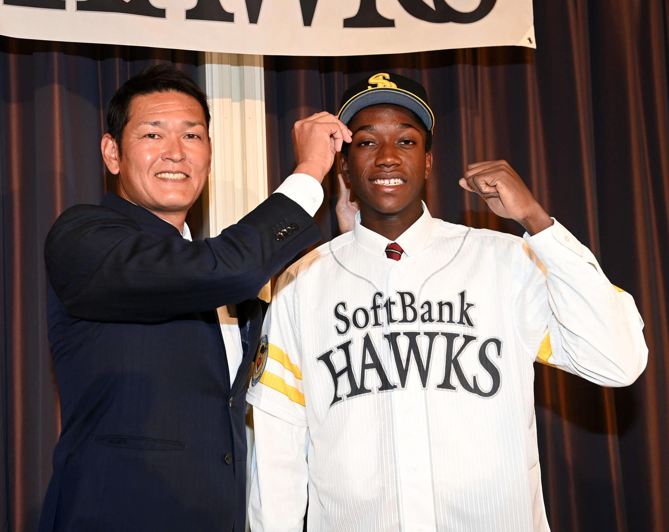 ソフトバンクと仮契約を結んだイヒネ（右）は永井スカウト部長から激励を受ける（撮影・前岡正明）