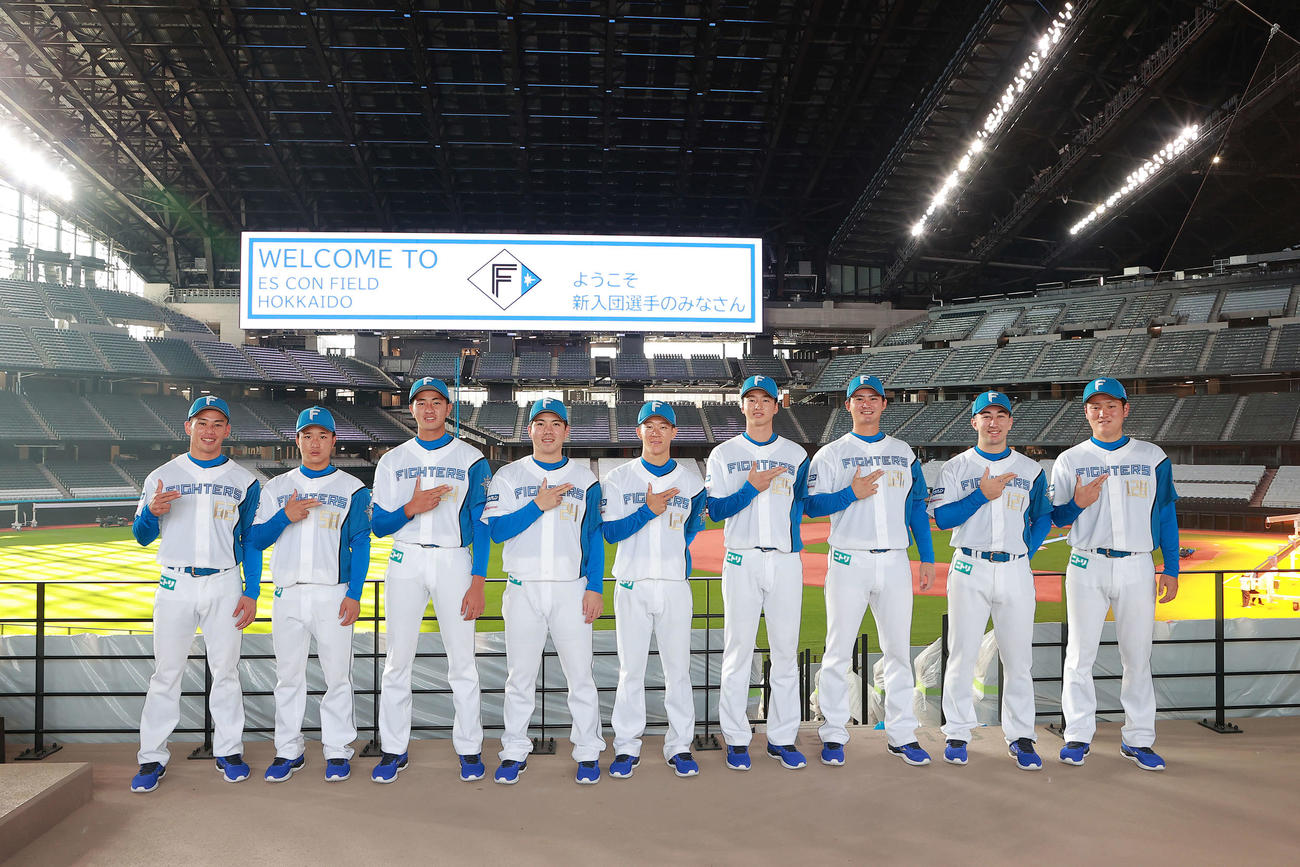 新球場のグラウンドをバックにポーズする新入団選手たち（球団提供）