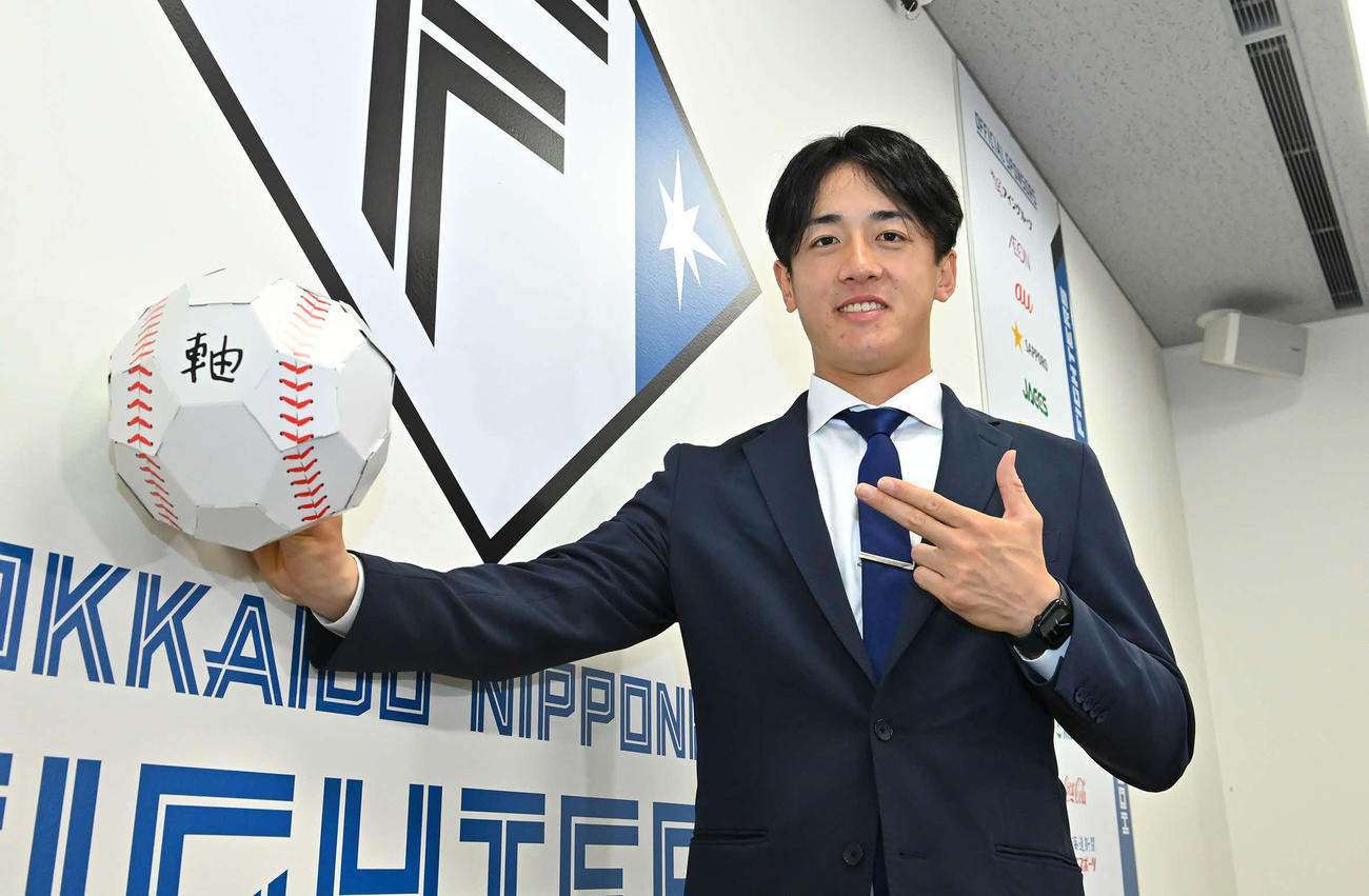 来季の目標「軸」と記したボールを手にポーズする日本ハム北山（代表撮影）