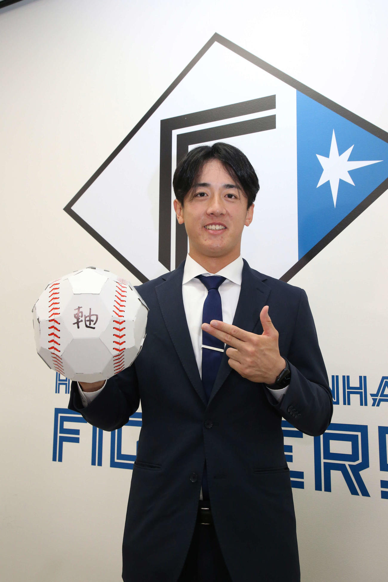 来季の目標「軸」と記したボールを手にポーズする日本ハム北山（代表撮影）