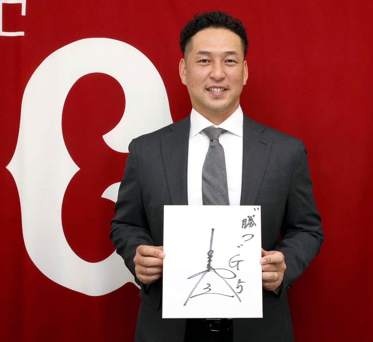 「勝つ」と書いた色紙を手に笑顔を見せる巨人中島（球団提供）