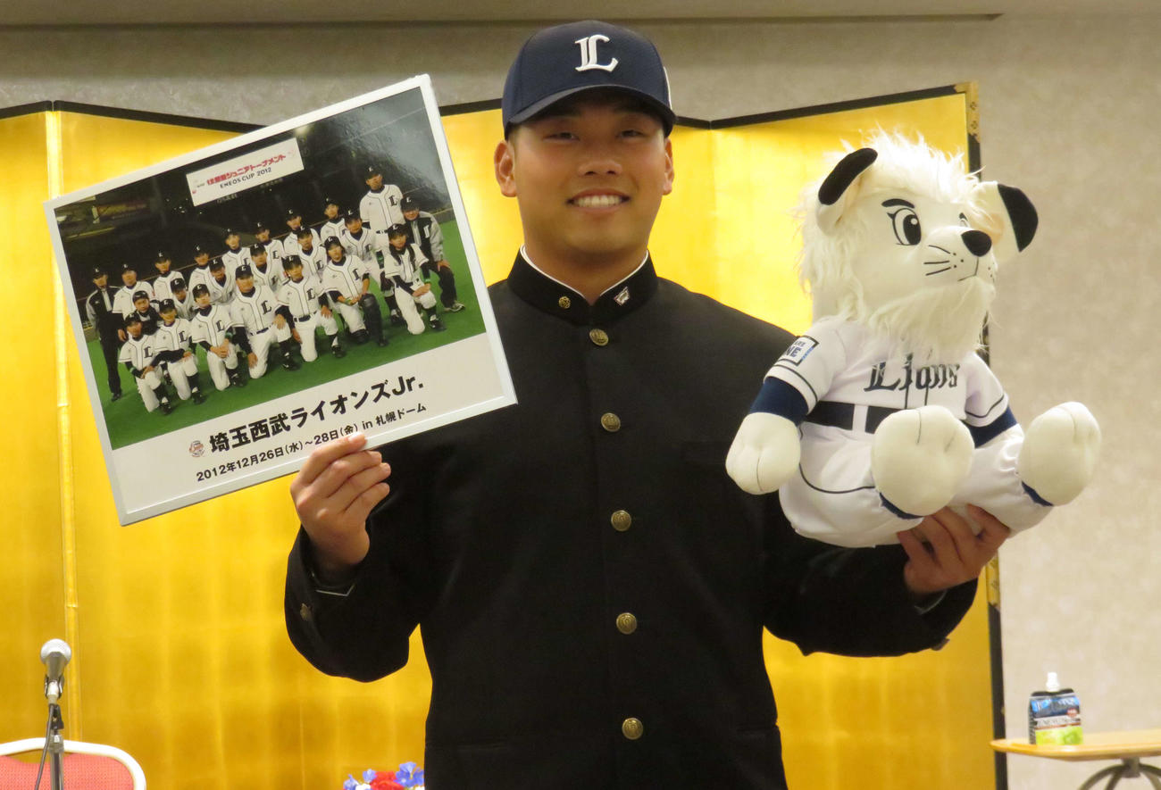 契約交渉を終え、ライオンズジュニア時代の写真とレオ人形を手に笑顔のドラフト1位・早大蛭間