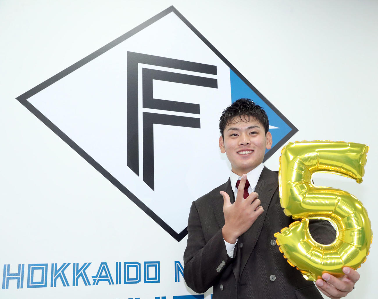 契約更改を終え、新しい背番号「5」を手にポーズを決め撮影に応じる日本ハム野村（撮影・佐藤翔太）