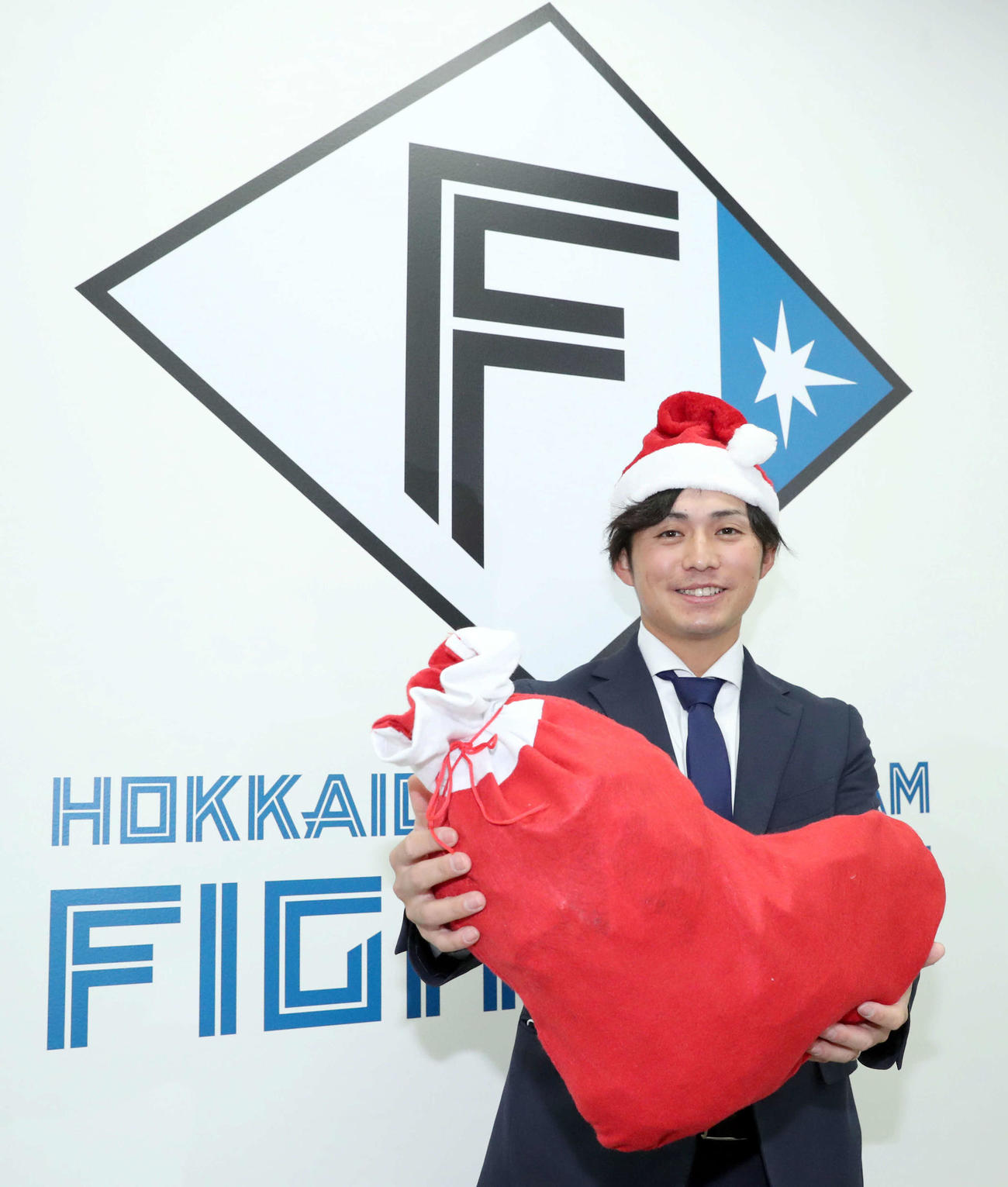 年俸倍増でサインし、サンタの装飾を身に付け笑顔を見せる日本ハム上川畑（代表撮影）
