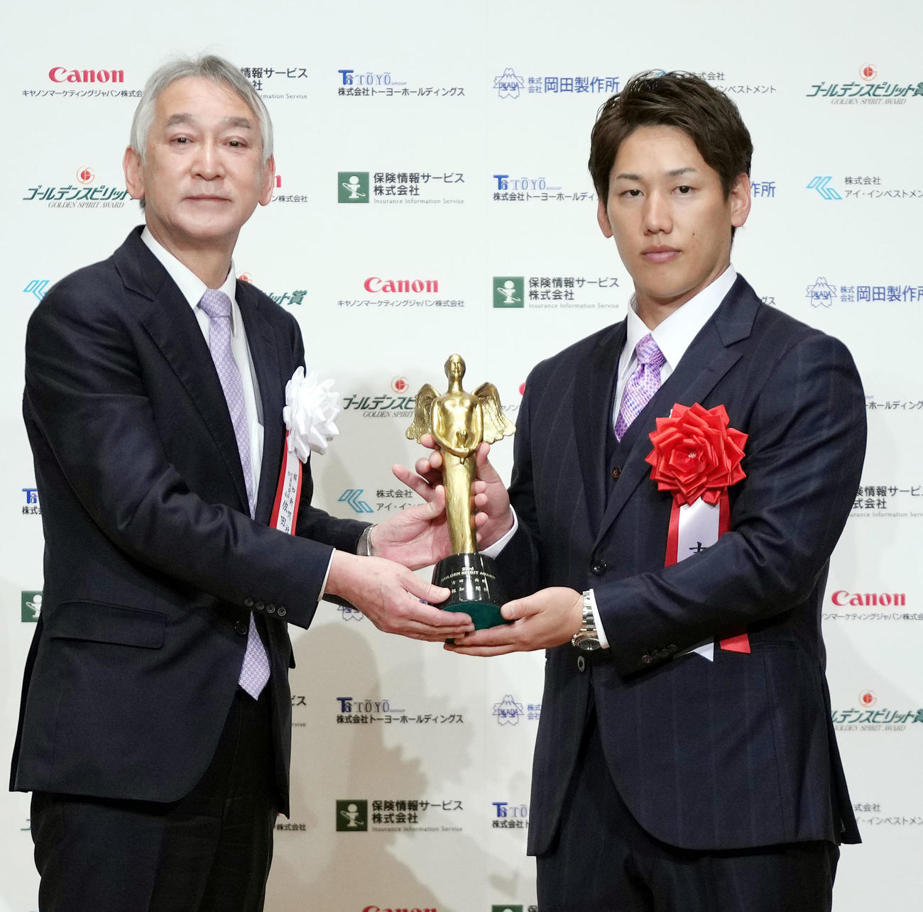 ゴールデンスピリット賞の表彰式で報知新聞社の依田社長（左）から記念像を受け取るオリックス吉田正（撮影・狩俣裕三）