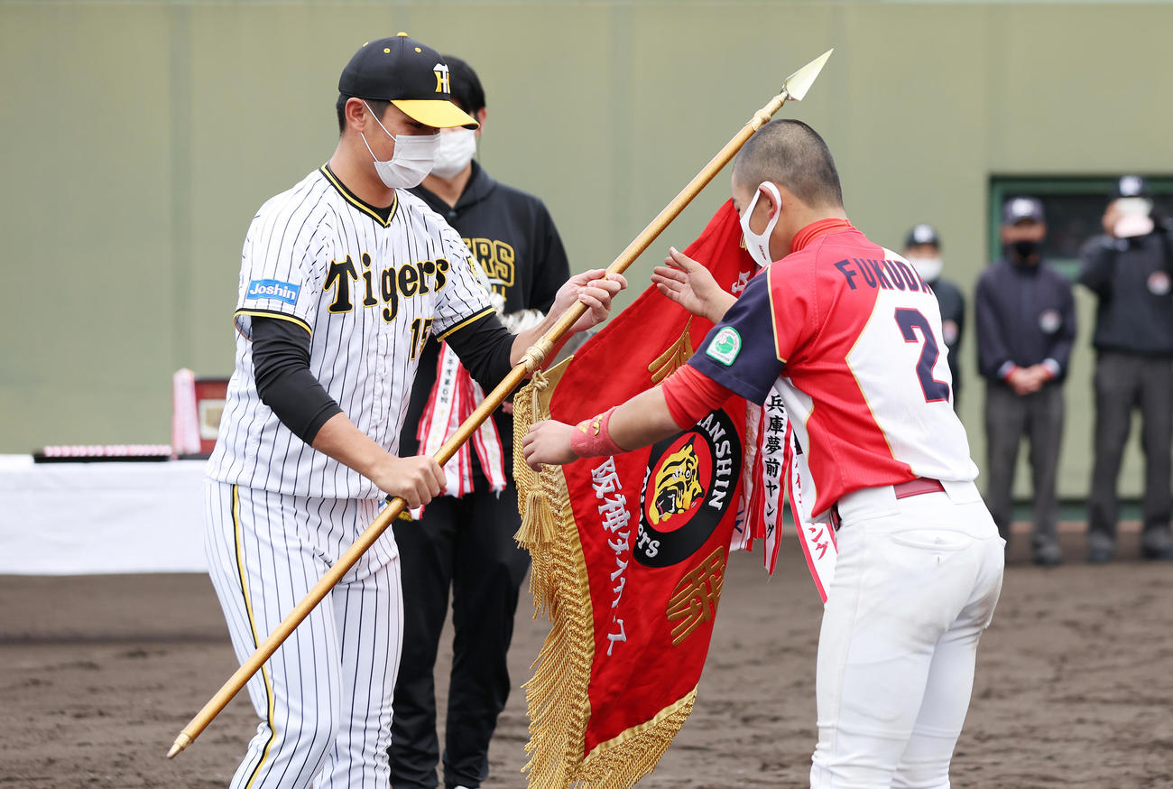 タイガースカップの表彰式でプレゼンターを務め、選手に優勝旗を渡す阪神西純（左）（撮影・前田充）