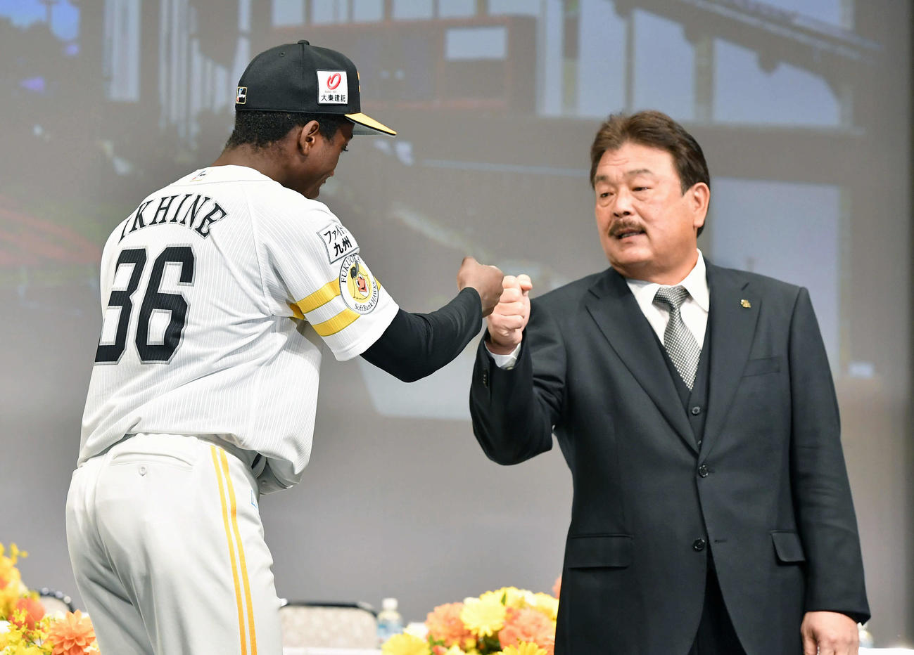 新入団選手発表会見で、藤本監督（右）とグータッチを交わしながら入場するイヒネ（撮影・岩下翔太）