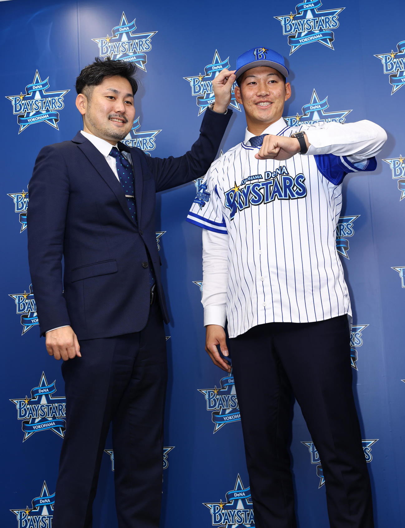 入団会見に臨んだDeNA京田（右）はユニホームに袖を通し「デスターシャ！」。左は萩原チーム統括本部長（撮影・垰建太）