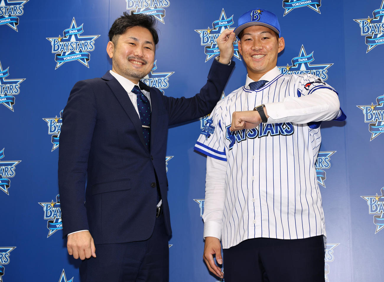 入団会見に臨んだDeNA京田（右）はユニホームに袖を通し「デスターシャ！」。左は萩原チーム統括本部長（撮影・垰建太）