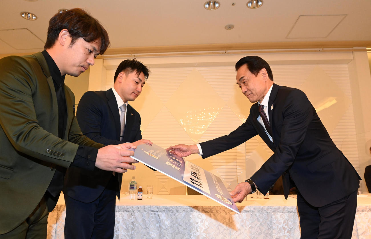 一般社団法人日本プロ野球選手会を代表して好本公益財団法人ドナルド・マクドナルド・ハウス・チャリティーズ・ジャパン評議員に支援金を贈呈する、左から小川と丸（撮影・前岡正明）