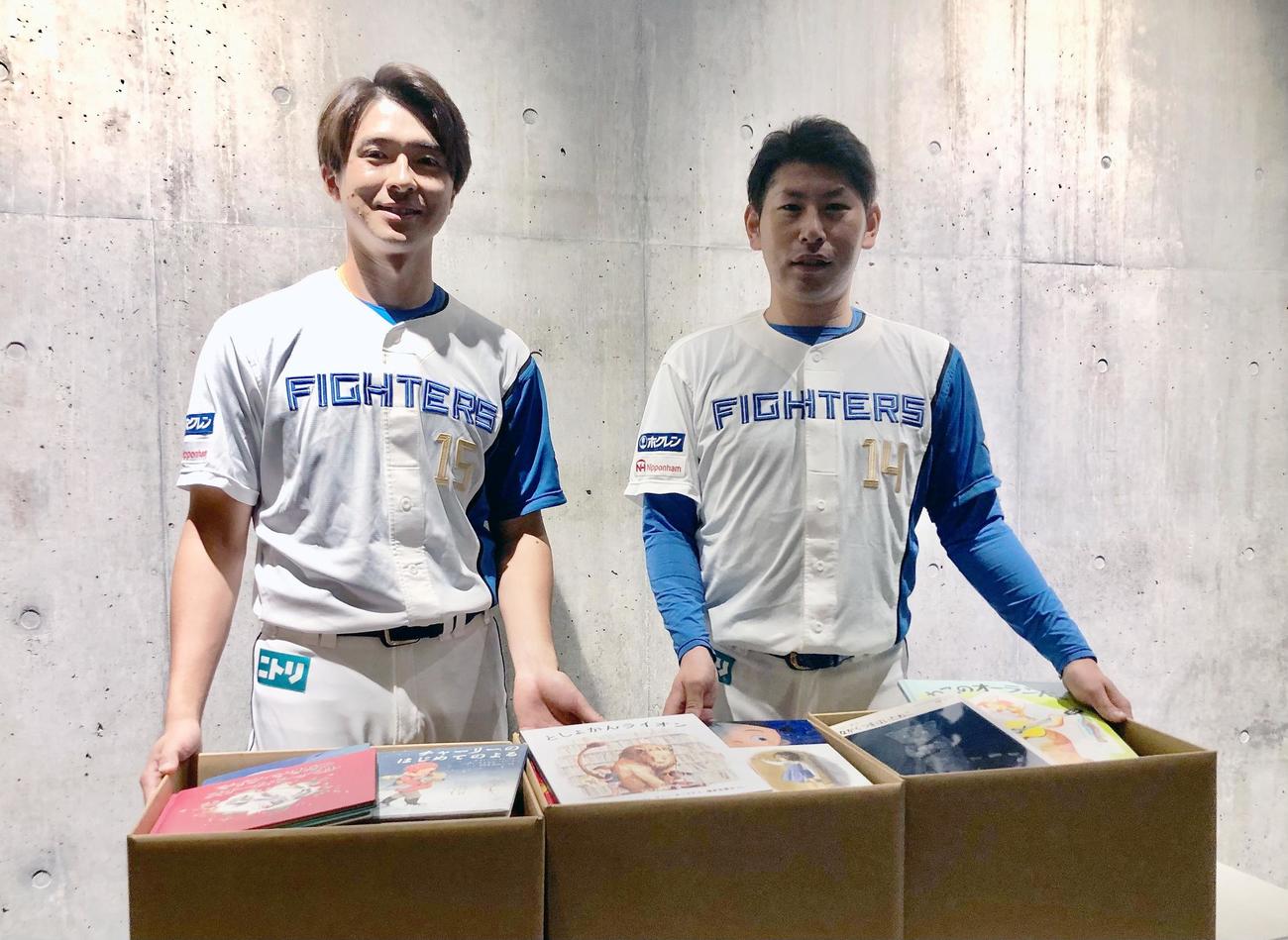 寄贈した書籍を前に笑顔の日本ハム上沢直之（左）と加藤貴之（球団提供）