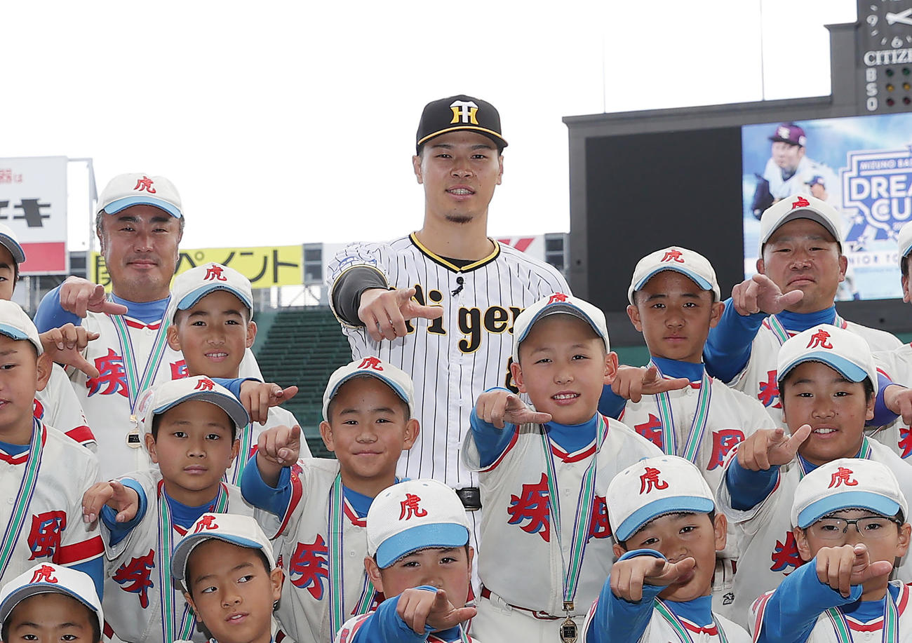 ミズノドリームカップの表彰式でプレゼンターを務め、優勝した北ナニワハヤテタイガースの選手たちと記念写真に納まる阪神佐藤輝（中央）（撮影・前田充）