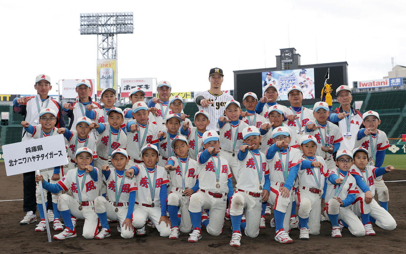 ミズノドリームカップの表彰式でプレゼンターを務め、優勝した北ナニワハヤテタイガースの選手たちと記念写真に納まる阪神佐藤輝（後列中央）（撮影・前田充）