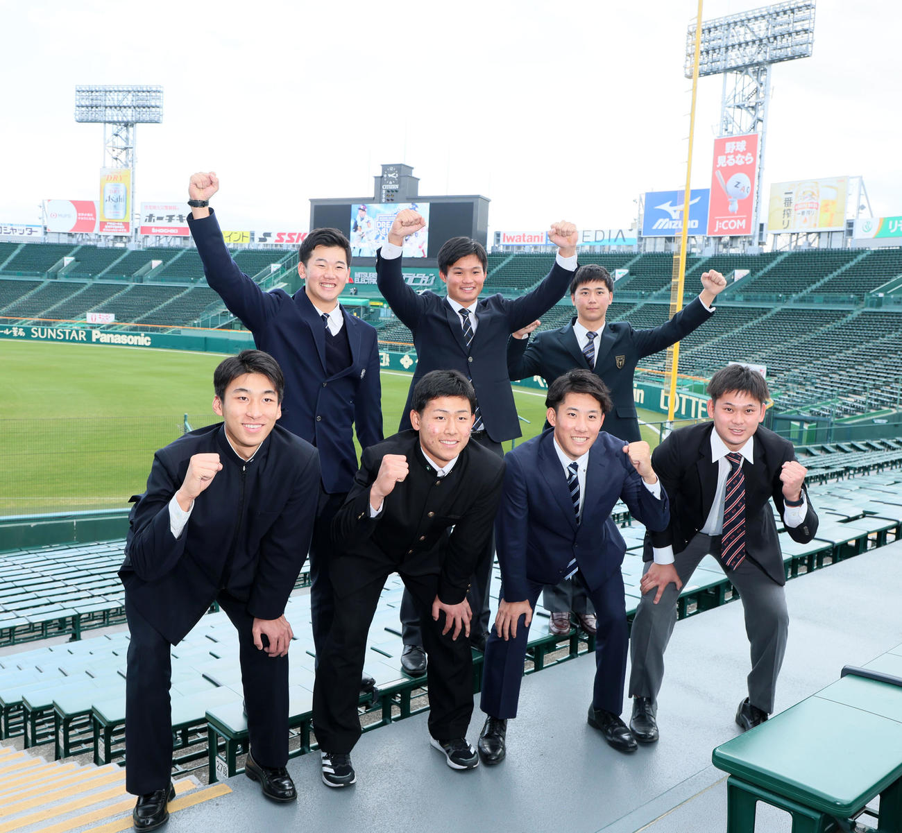 施設見学を行いアルプススタンドで記念写真に納まる阪神新入団の前列左から茨木、戸井、富田、野口、後列左から門別、森下、井坪（撮影・加藤哉）