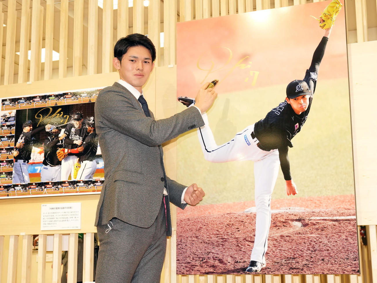 日本橋三越で行われる第63回2022年報道写真展のオープニングで完全試合達成時の写真にサインをするロッテ佐々木朗（撮影・狩俣裕三）