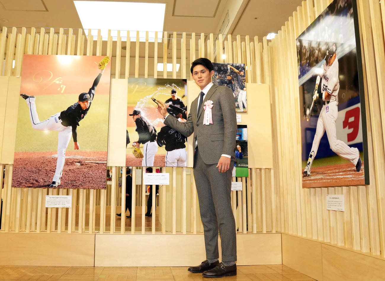 日本橋三越で行われる第63回2022年報道写真展のオープニングで完全試合達成時の写真にサインをするロッテ佐々木朗（撮影・狩俣裕三）
