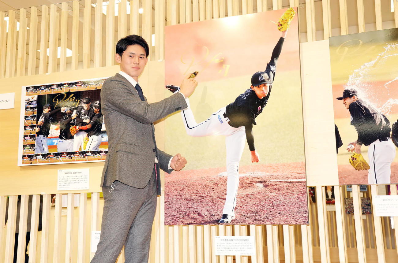日本橋三越で行われる第63回2022年報道写真展のオープニングで完全試合達成時の写真にサインをするロッテ佐々木朗（撮影・狩俣裕三）