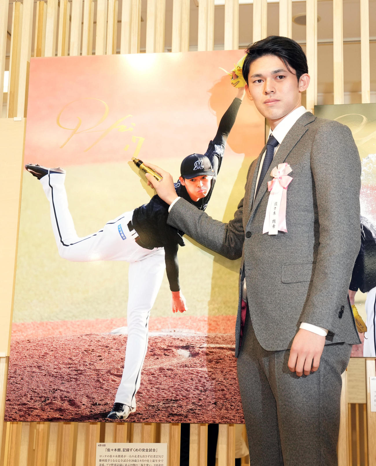 日本橋三越で行われる第63回2022年報道写真展のオープニングで完全試合達成時の写真にサインをするロッテ佐々木朗（撮影・狩俣裕三）