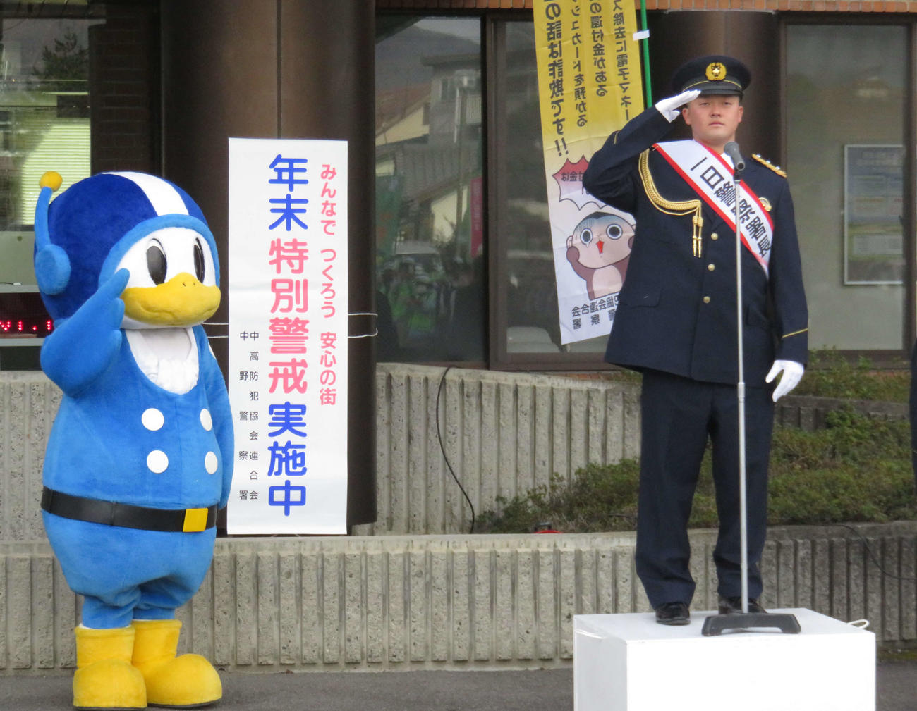 一日警察署長に任命され敬礼するDeNA牧秀吾内野手。左は長野県警マスコット・ライポくん