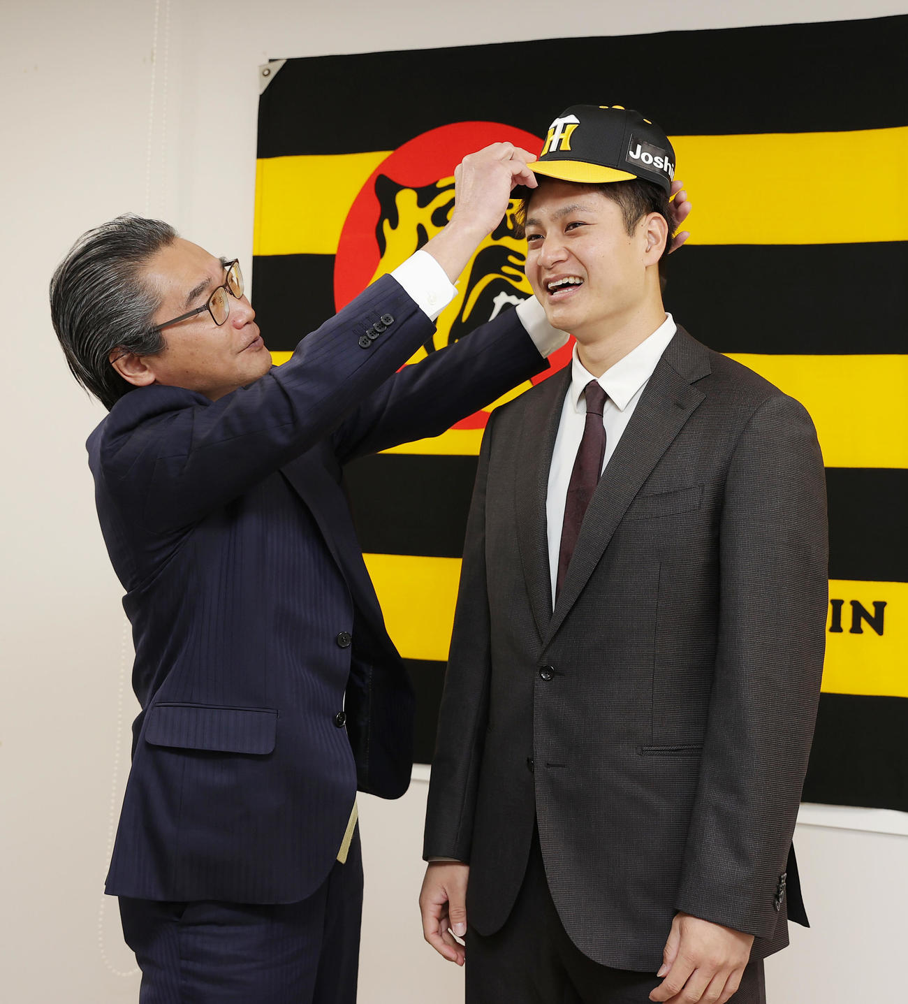 入団会見を終え嶌村球団本部長（左）に帽子をかぶせてもらう阪神大竹（撮影・前田充）