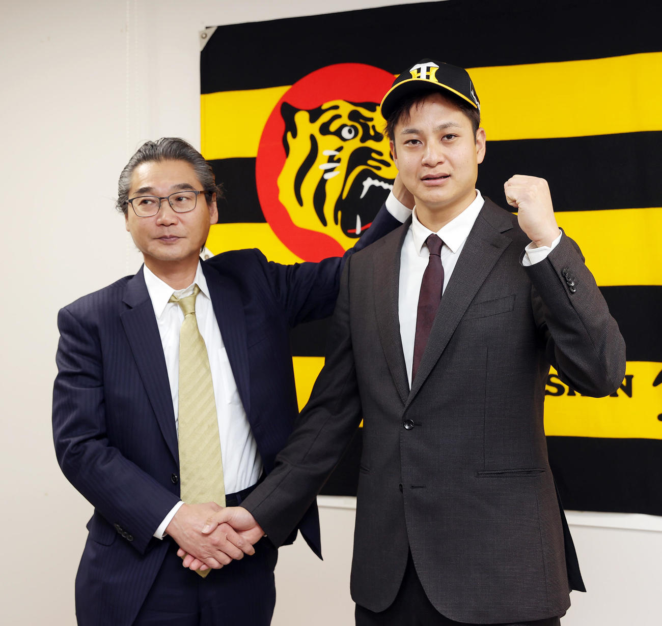 入団会見を終え嶌村球団本部長（左）と握手を交わしガッツポーズする阪神大竹（撮影・前田充）