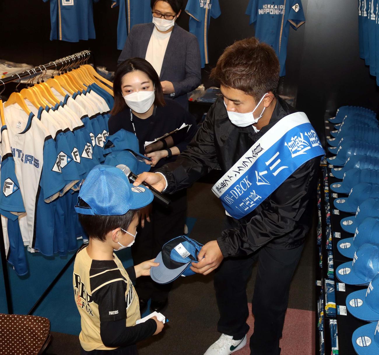 来場者の子どものキャップのサイズを確認する日本ハム今川（右）（撮影・永野高輔）