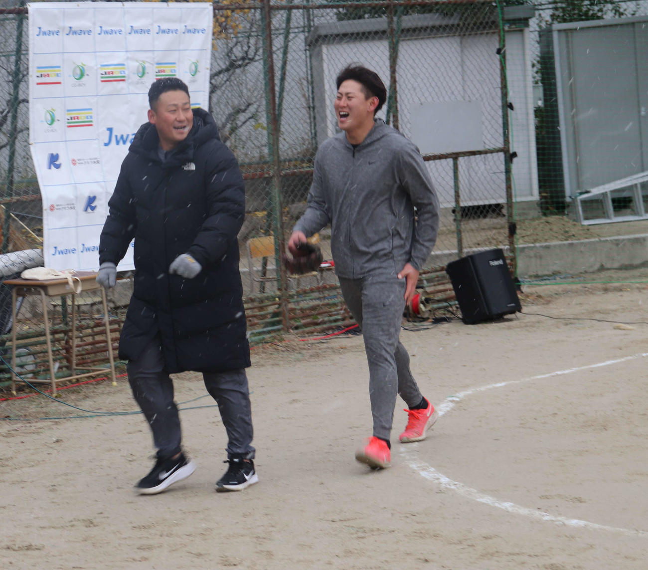 雪が降りしきる極寒の中、笑顔で野球教室の会場から引き揚げる巨人中田（左）と日本ハム姫野（撮影・小早川宗一郎）