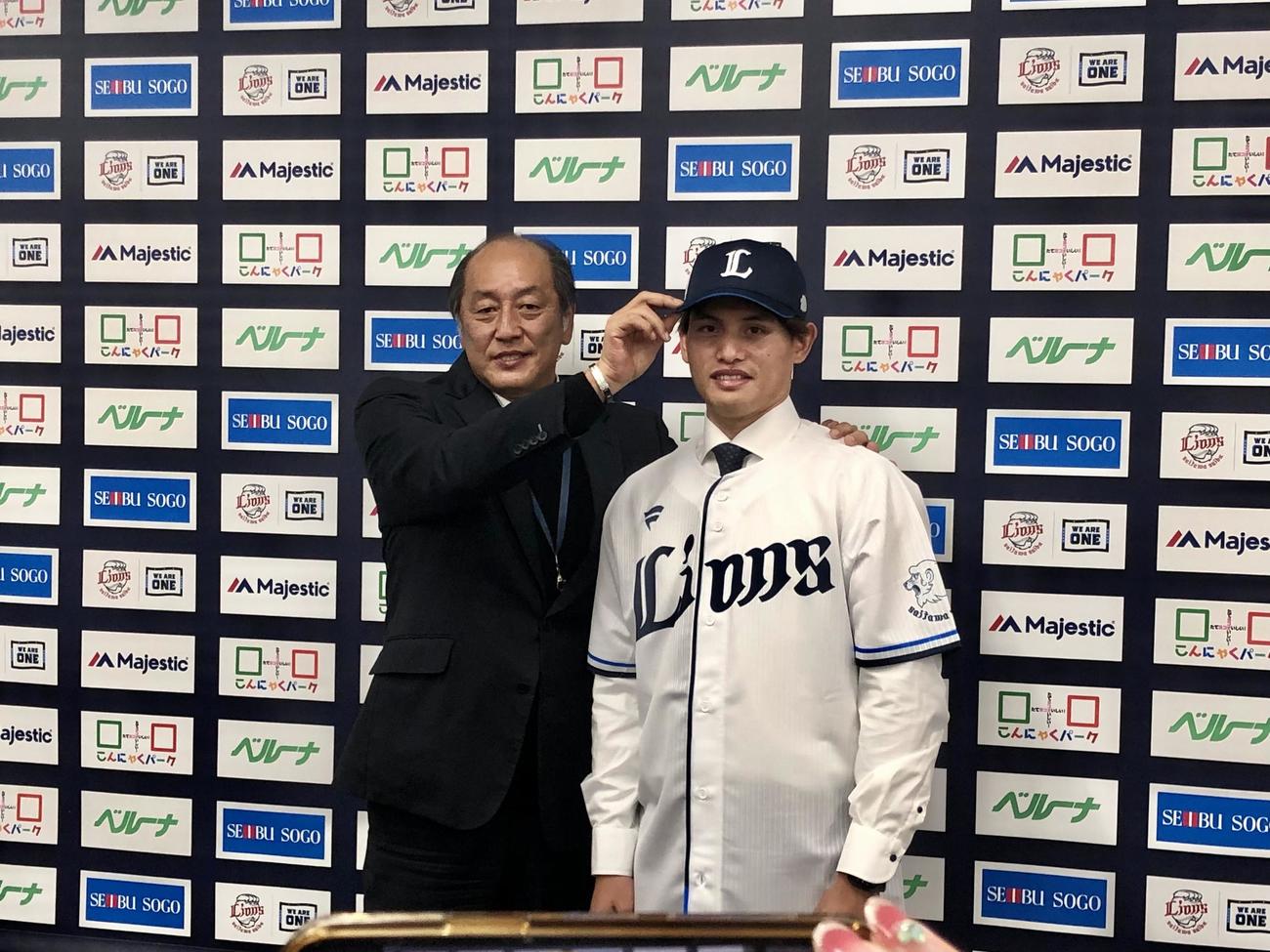 西武渡辺GM（左）から帽子を被せてもらう張奕（撮影・上田悠太）