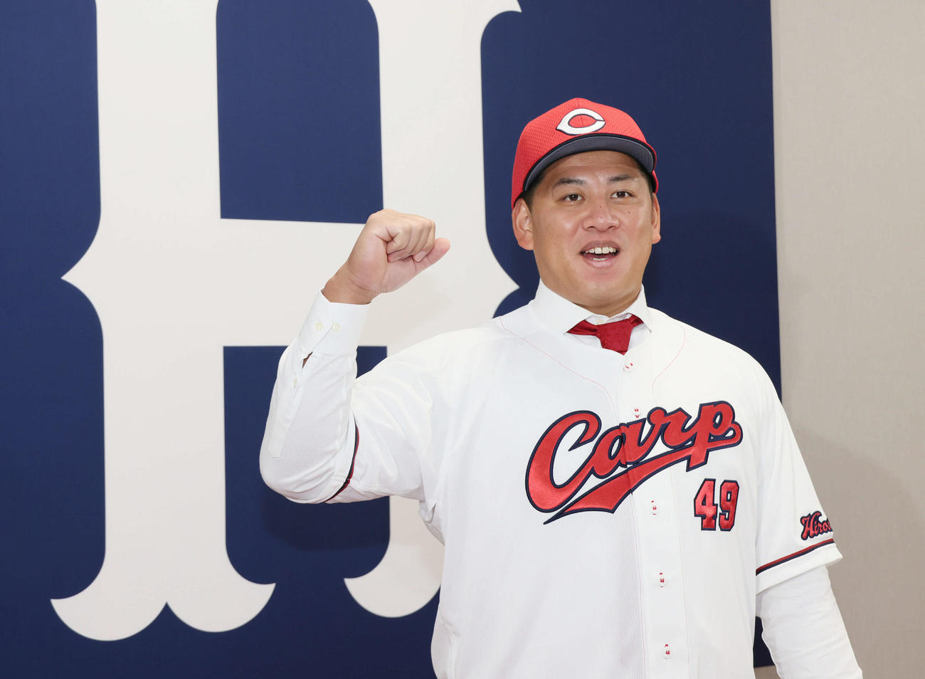 現役ドラフトで巨人から広島への移籍が決まり、入団会見を行った戸根。広島のユニホームに袖を通しポーズを決める（撮影・加藤孝規）
