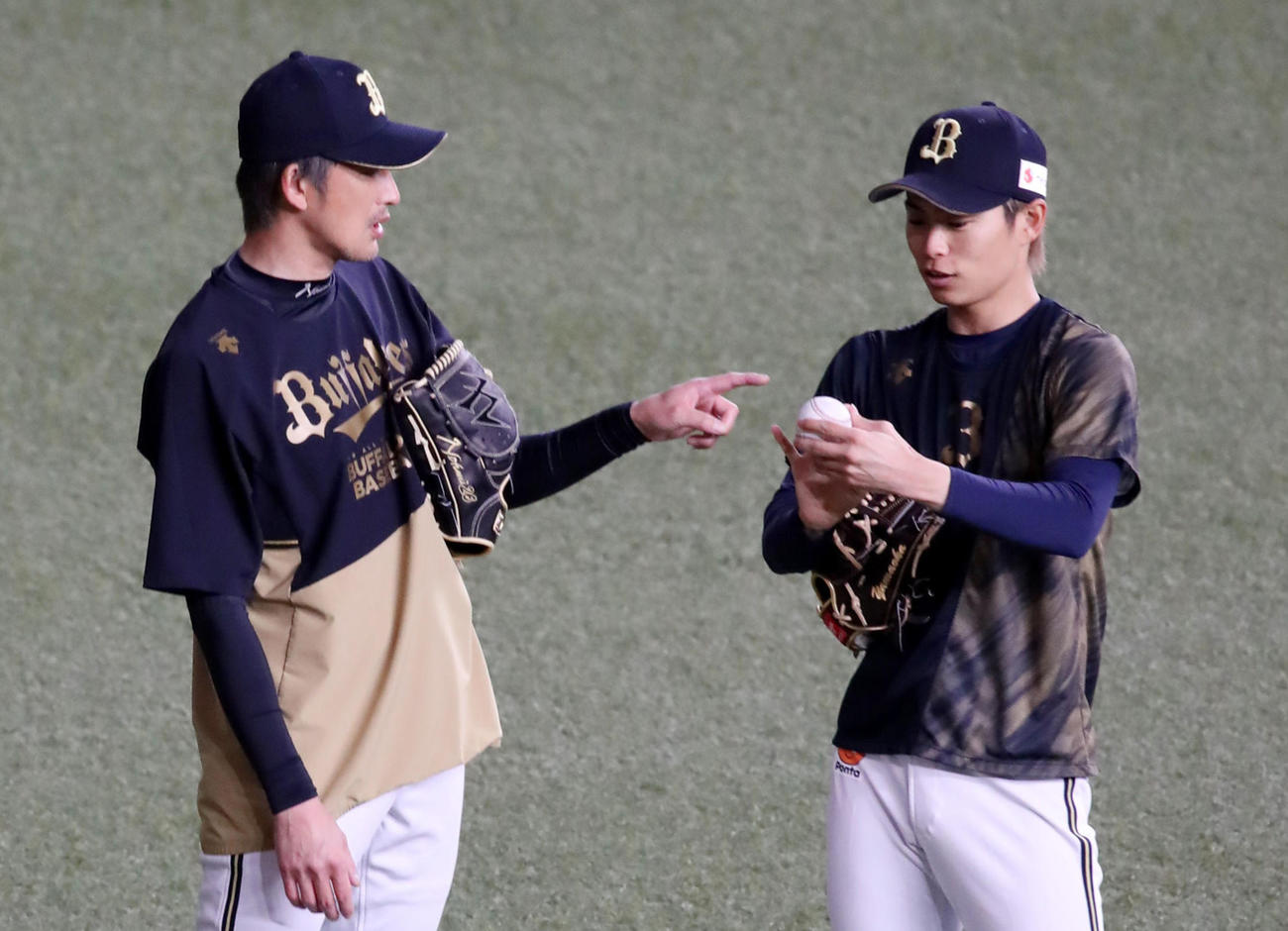 能見（左）からボールの握りについてアドバイスされる山岡（2022年3月19日撮影）