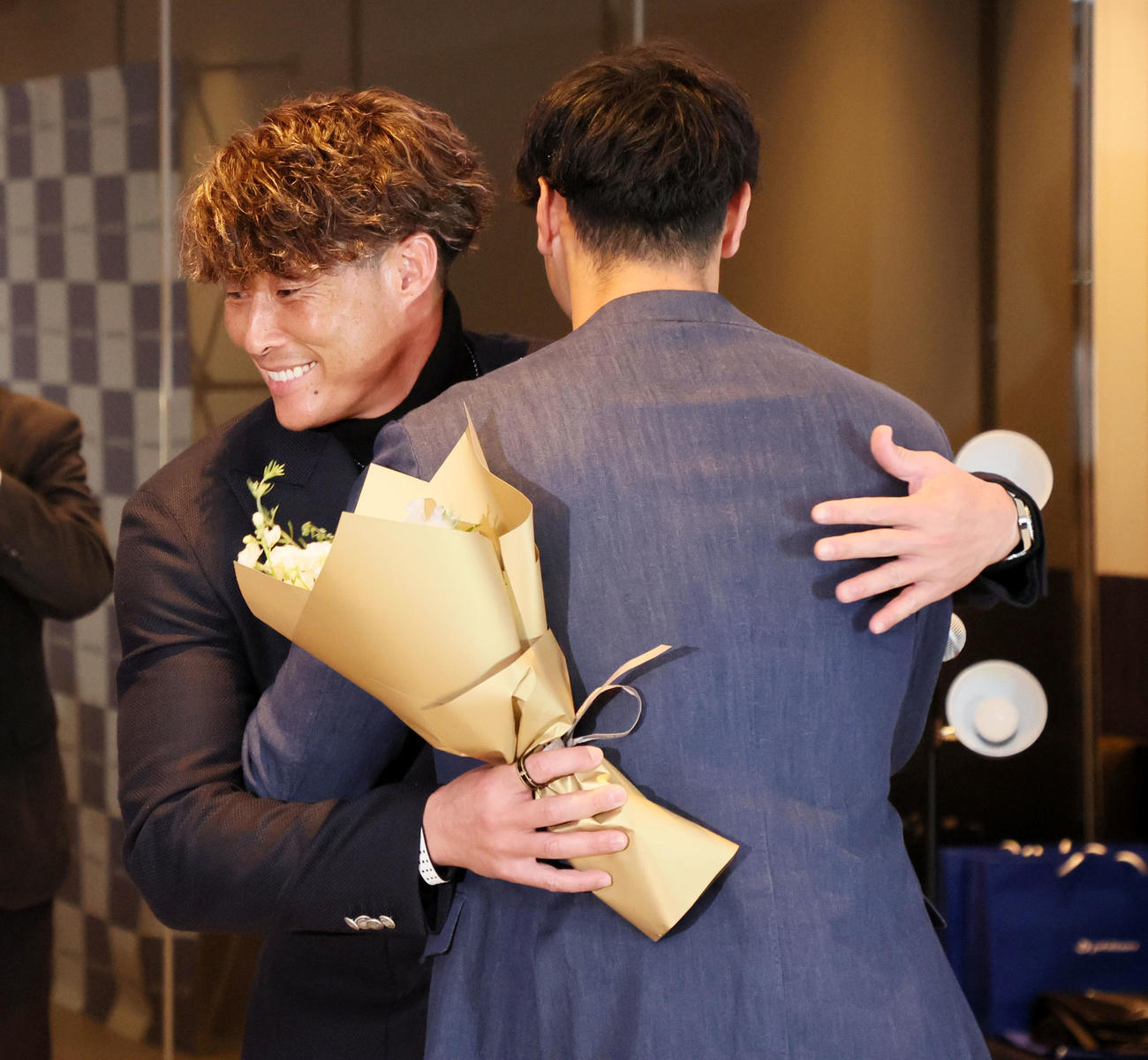 ファイテン社のファンミーティングで佐藤輝（右）から現役引退の花束を受け取り抱擁する糸井氏（撮影・加藤哉）