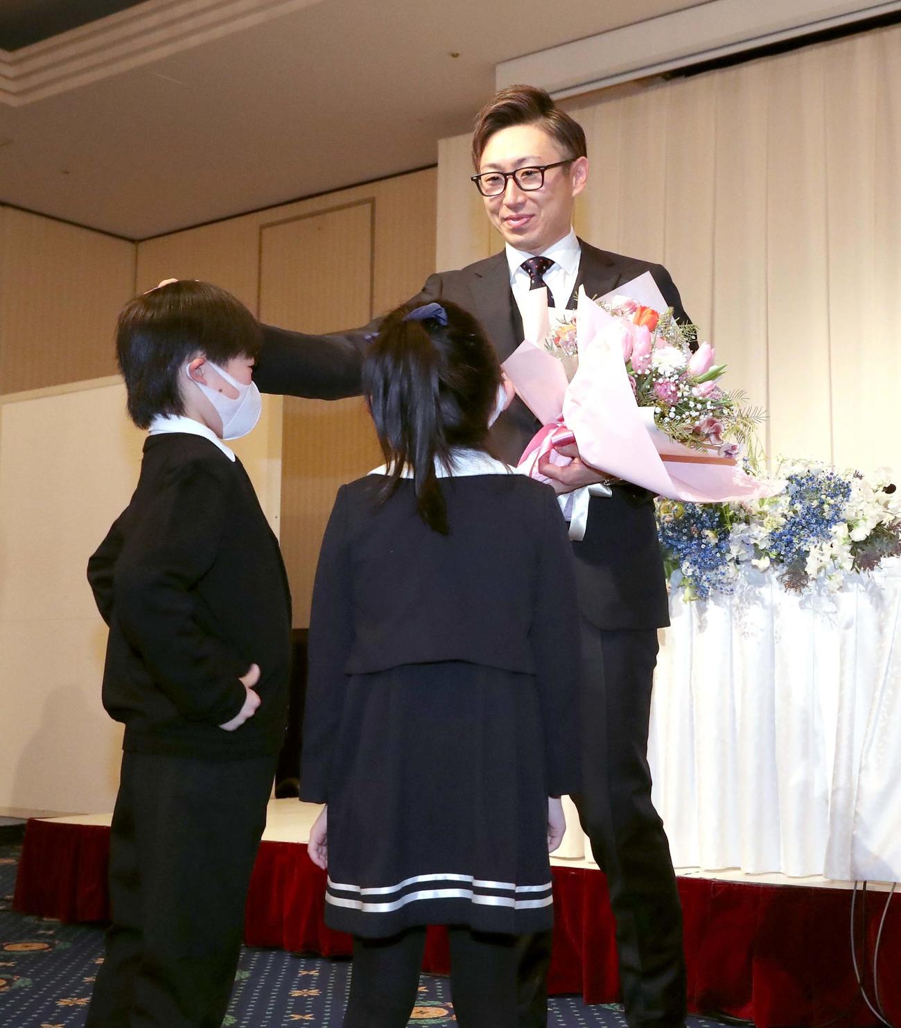 引退会見で長男壱覇くん（左）、長女未來ちゃんから花束を受け取る日本ハム金子（撮影・黒川智章）