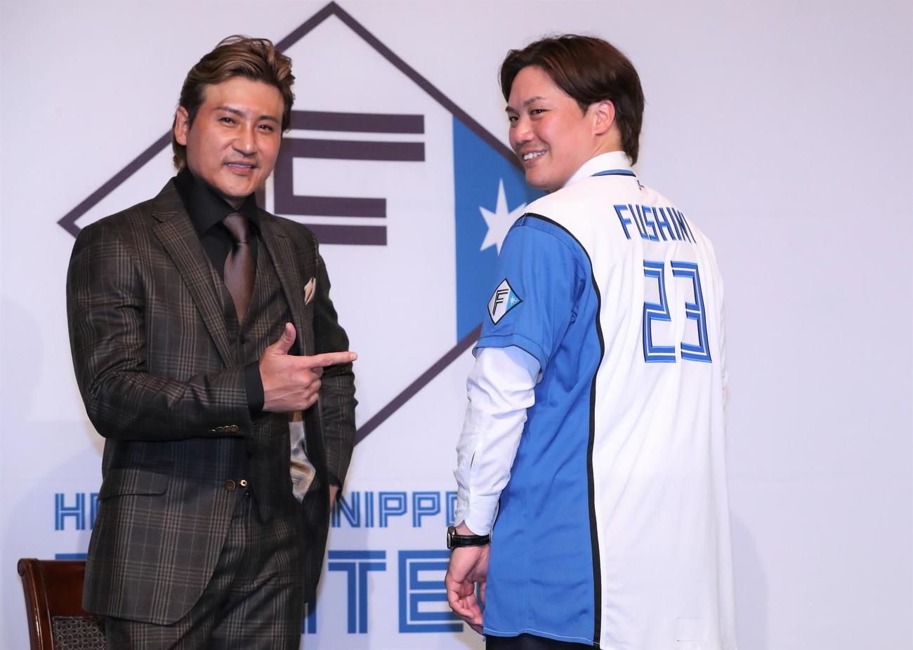 日本ハムのユニホームに袖を通し新庄剛志監督（左）とポーズをとる伏見（2022年11月24日撮影）