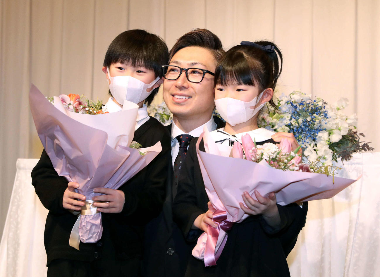 引退会見で長男壱覇くん（左）長女未來ちゃんから花束を受け取り笑顔の日本ハム金子（撮影・黒川智章）