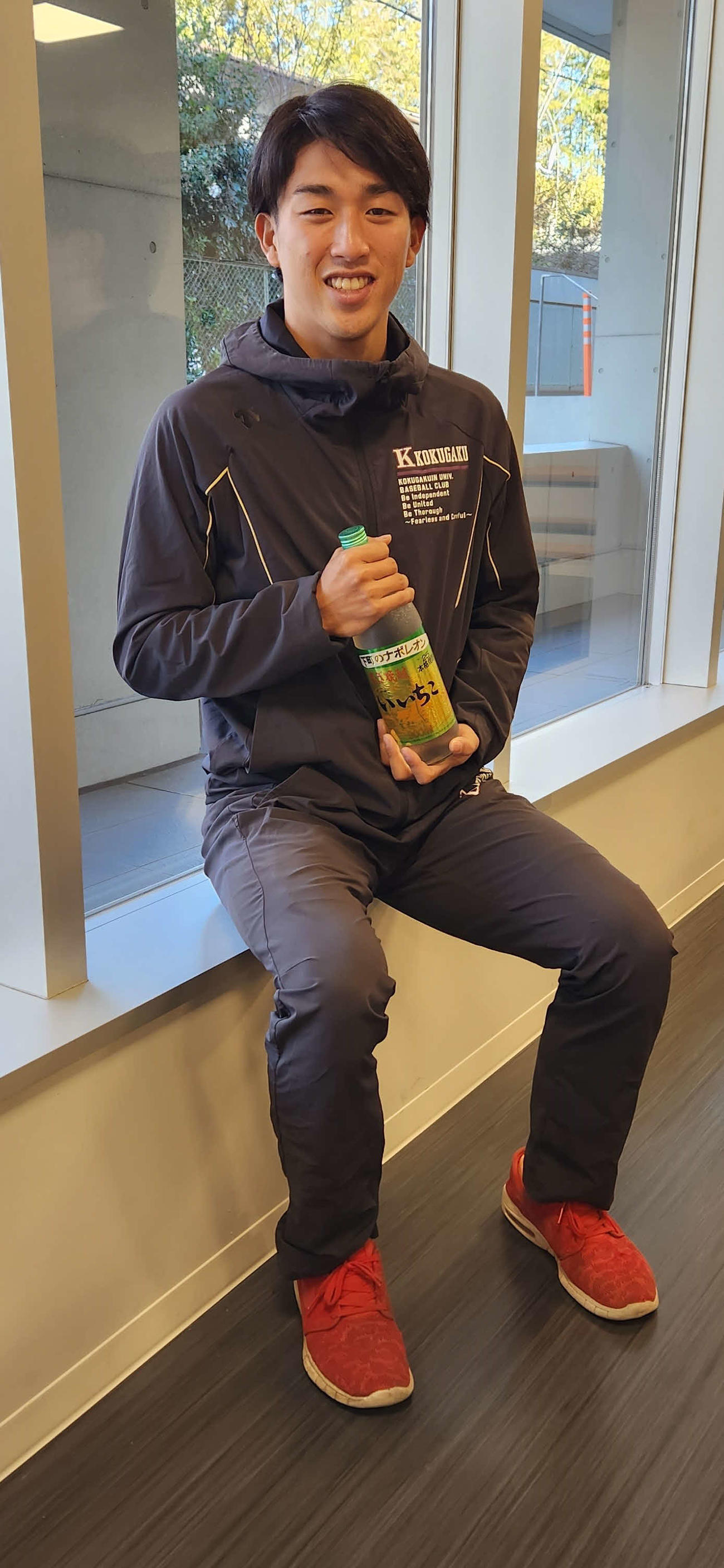 酒造会社に就職が決まり、自社商品の「いいちこ」を片手に笑顔を見せる国学院大・主将の古江（撮影・保坂淑子）