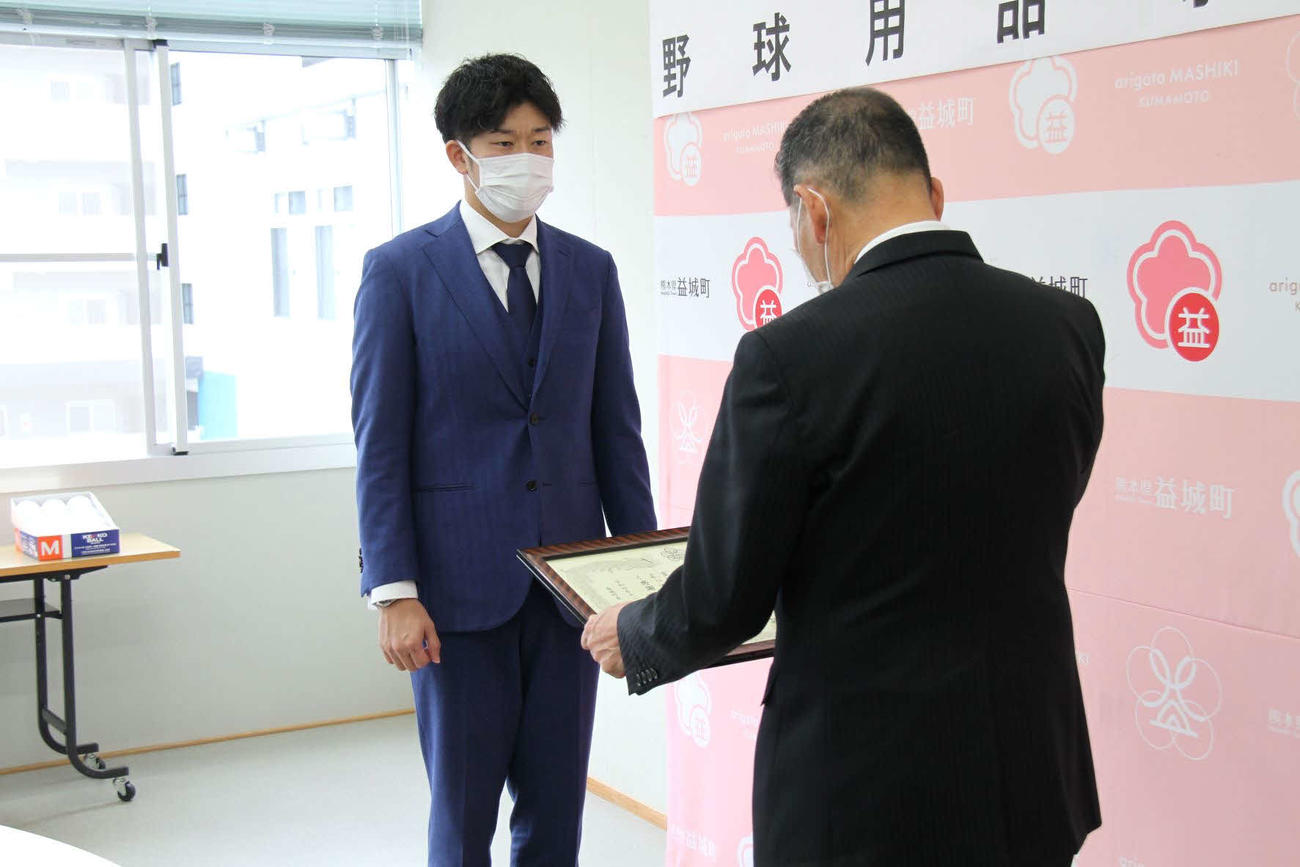 熊本県益城町に野球用品等の寄贈を行い、西村町長（右）から感謝状を受け取る岩貞（球団提供）