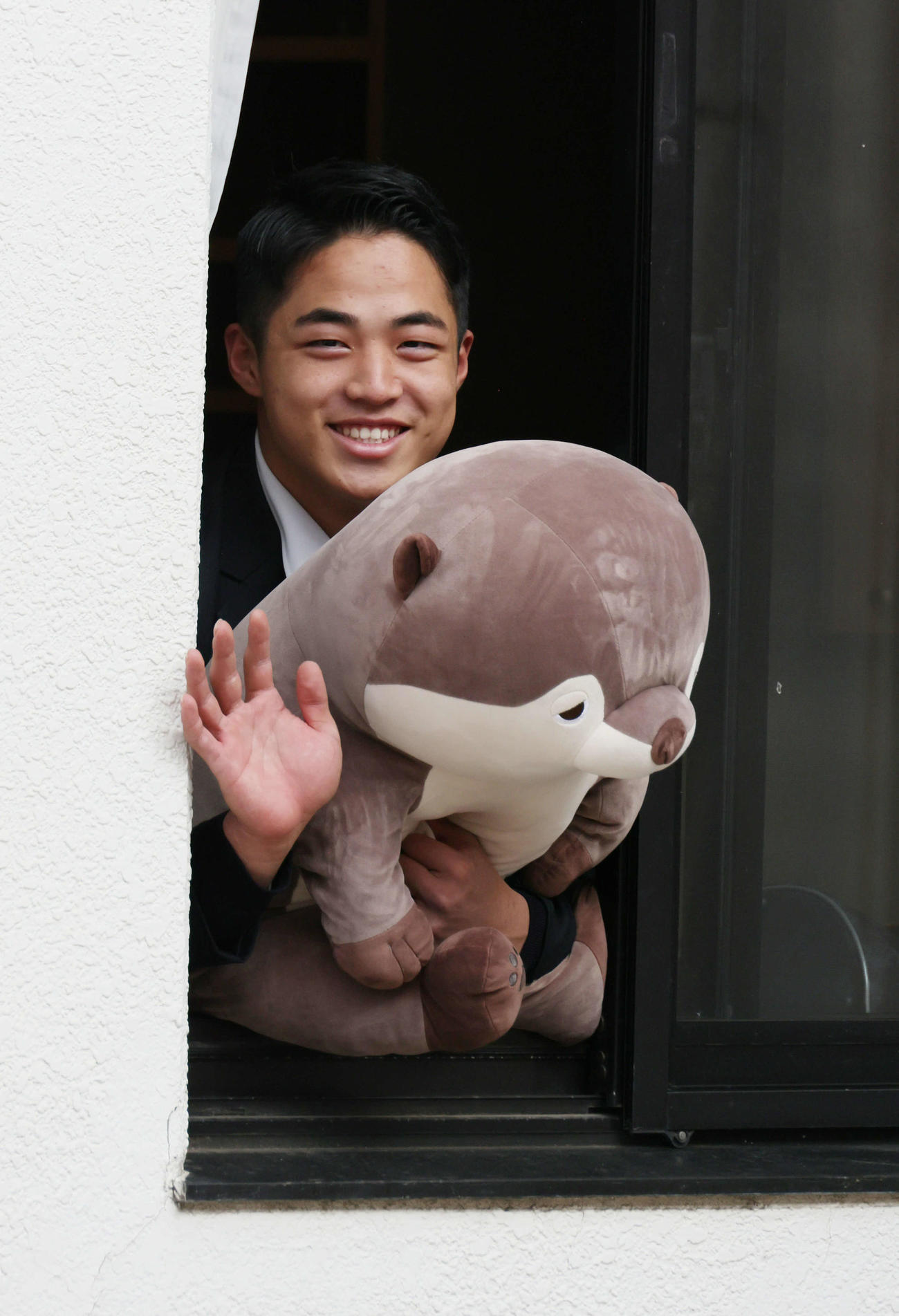 カワウソのぬいぐるみを手に寮の窓から手を振るドラフト2位の内田（撮影・加藤孝規）