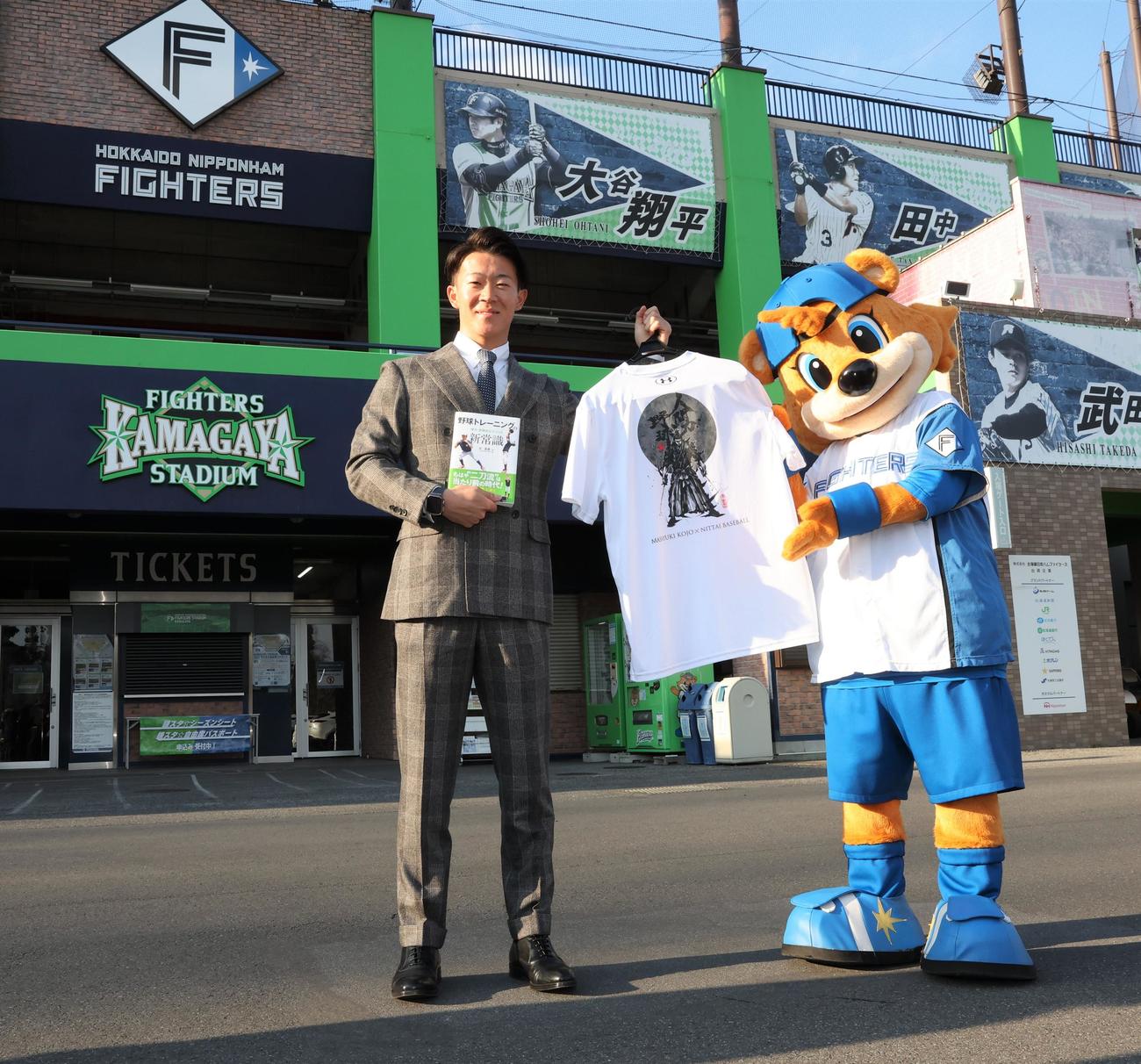 宮本武蔵をあしらった二刀流Tシャツを手にし、大谷の看板を背に意気込む日本ハム矢沢（撮影・黒川智章）