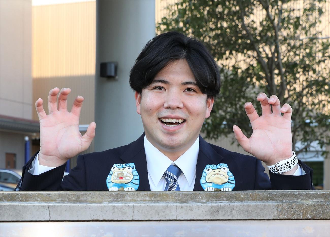 持参したシーサーの置物を前に「シーサーポーズ」をとる日本ハム金村（撮影・黒川智章）
