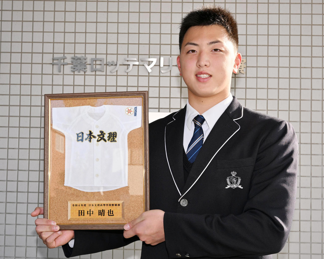 額に入った日本文理ユニホームを手に笑顔を見せるロッテドラフト3位田中