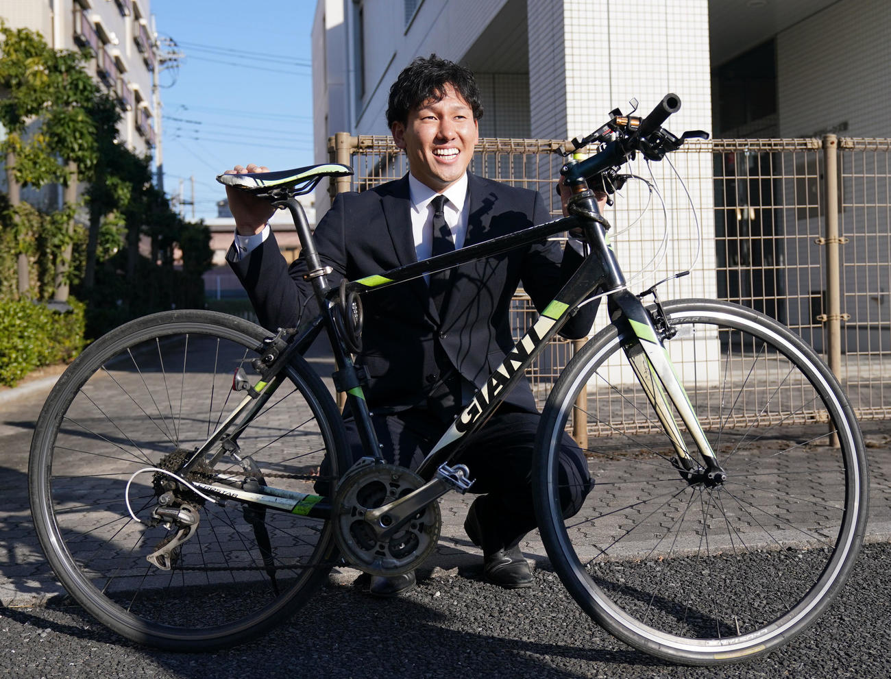 入寮する際に持ち込んだ自転車を手に笑顔を見せる（撮影・横山健太）