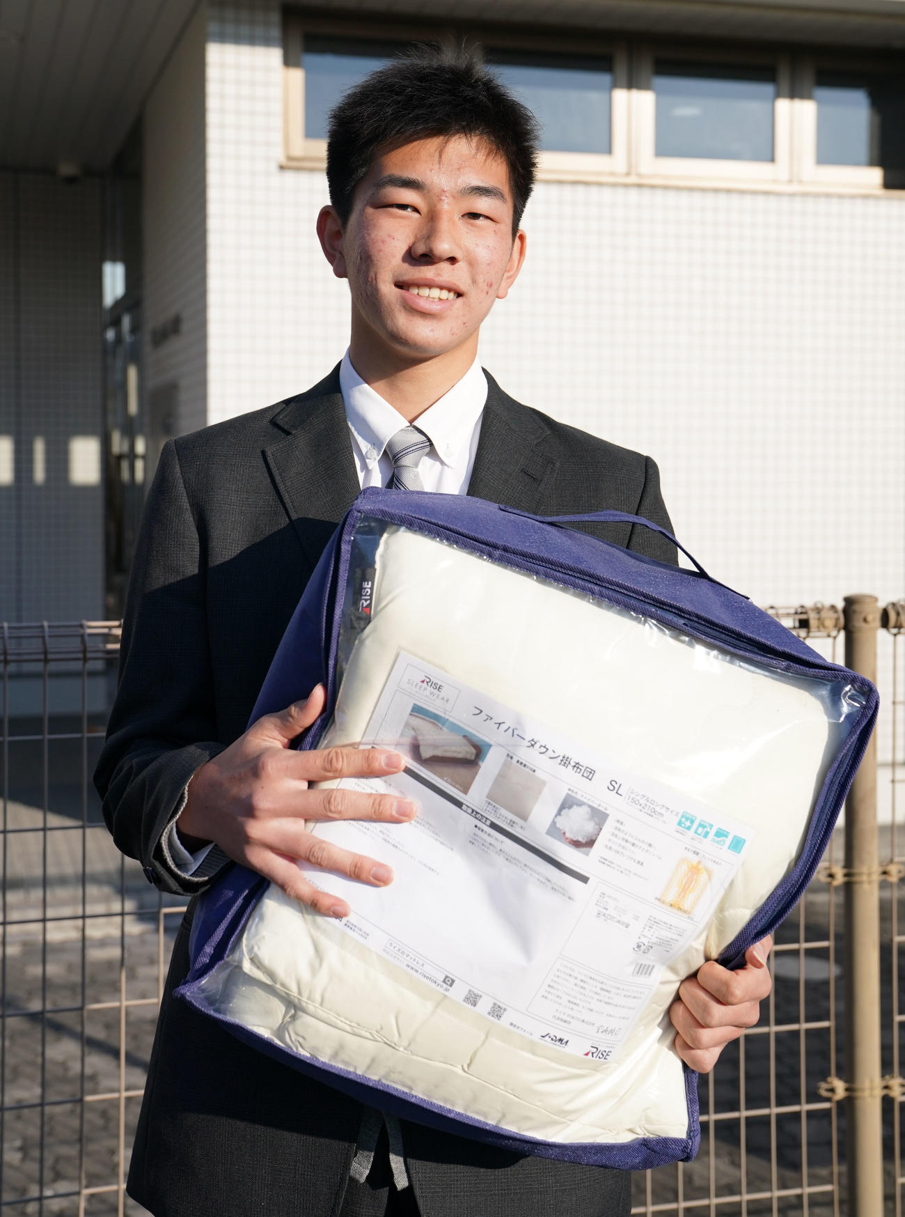 布団を手に笑顔を見せるロッテドラフト育成1位吉川（撮影・横山健太）