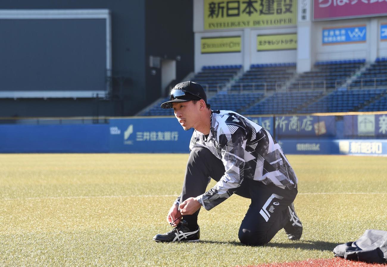 スパイクのひもを結ぶロッテ高部（撮影・鈴木正章）