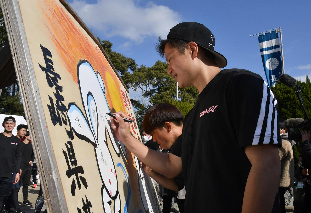 記念撮影を終え、絵馬にサインを書く阪神大竹（撮影・岩下翔太）